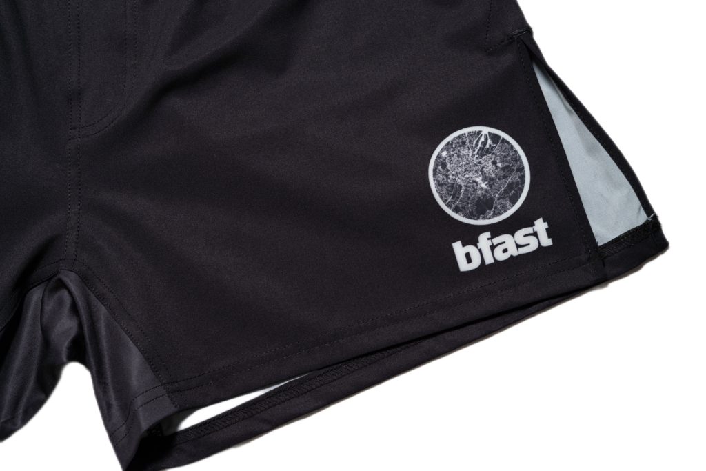 Close-up of black BFAST Essential Shorts showing the side split and logo